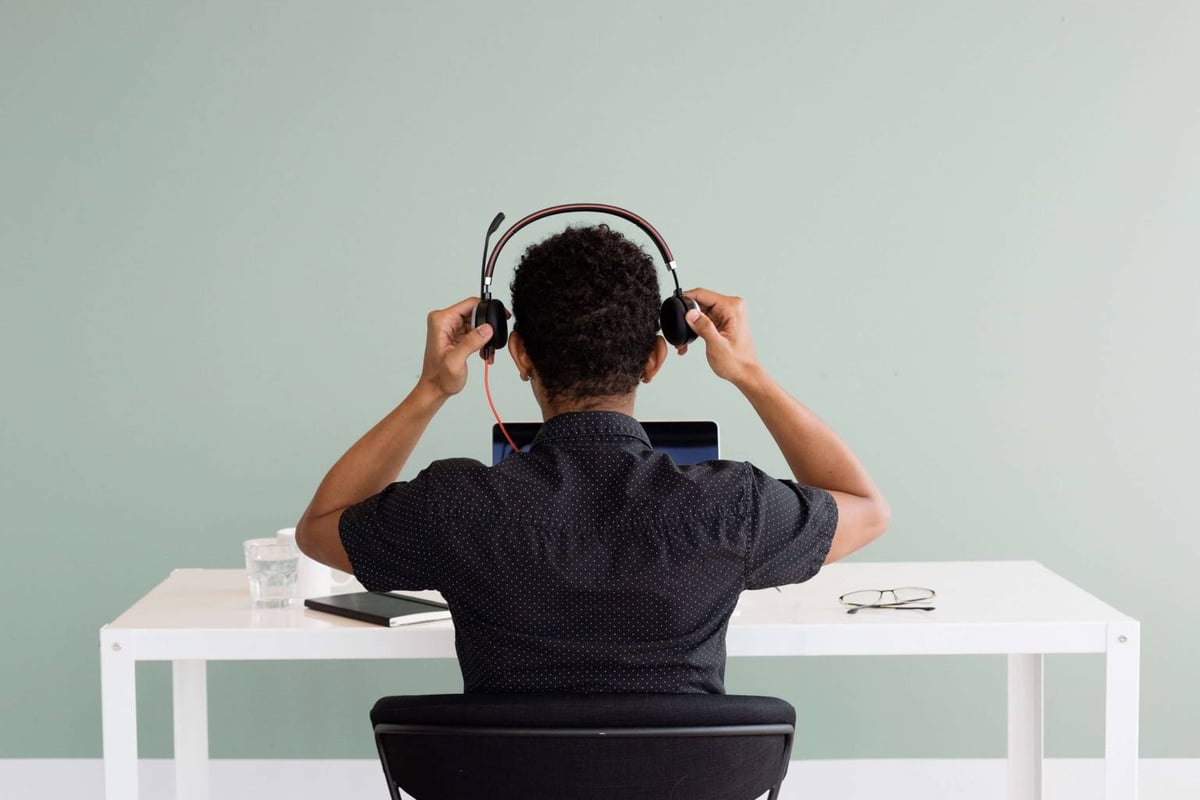 A man at a desk with headphones, engaged in communication, reflecting prompt and respectful customer service.