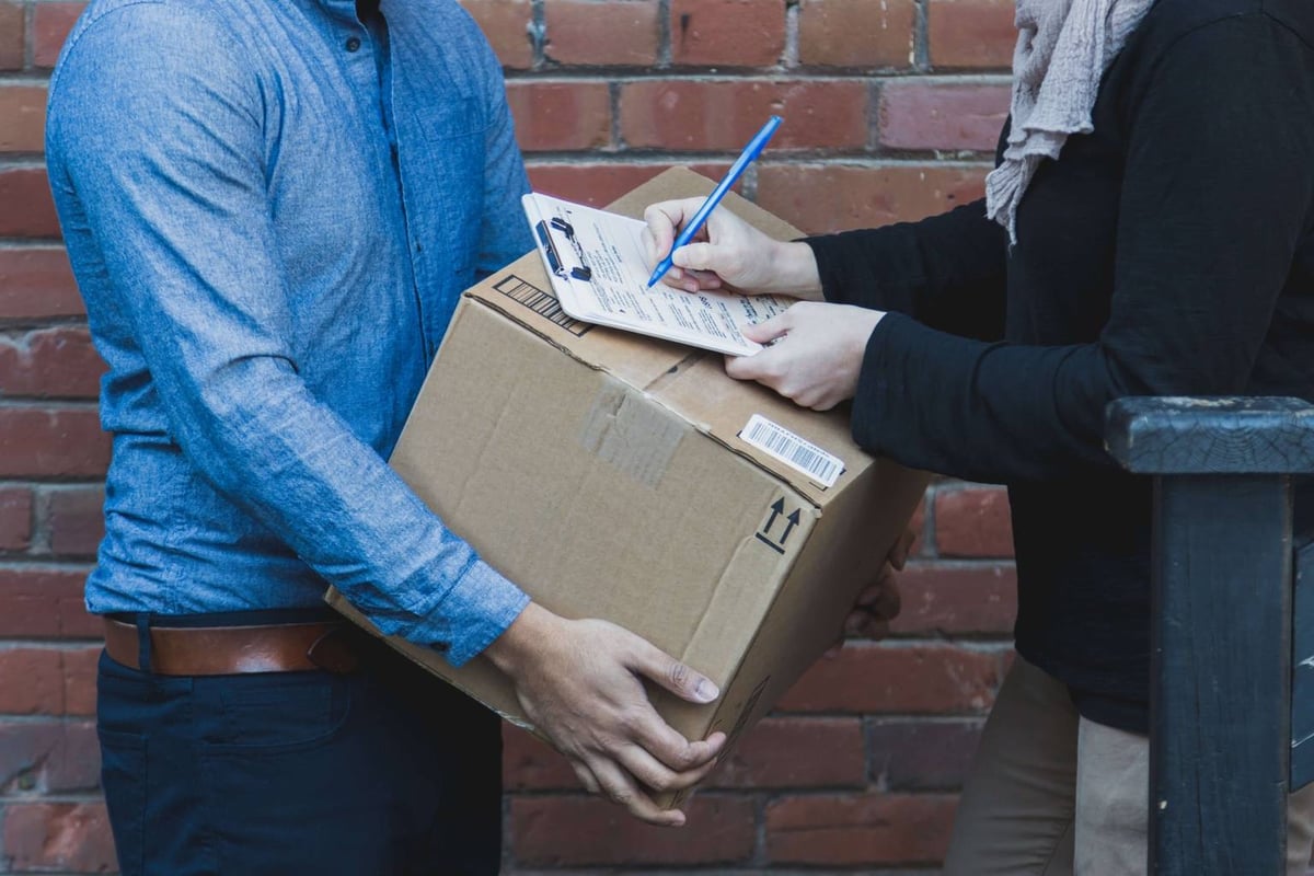 A man and woman grasp a box and a pen, reflecting their commitment to precision and attention to detail in their work.