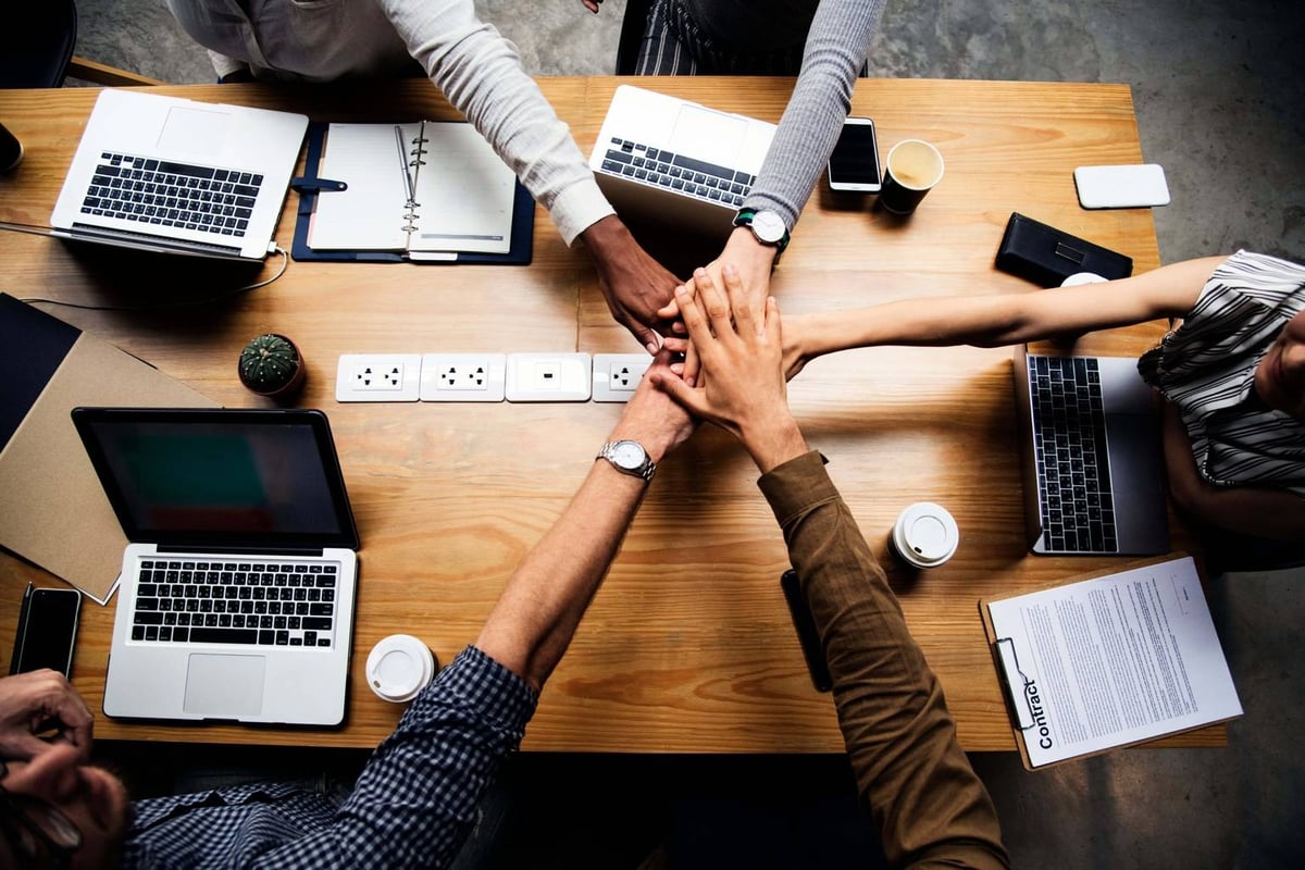 Business team members seated at a table with laptops, working together to surpass goals and provide outstanding value.